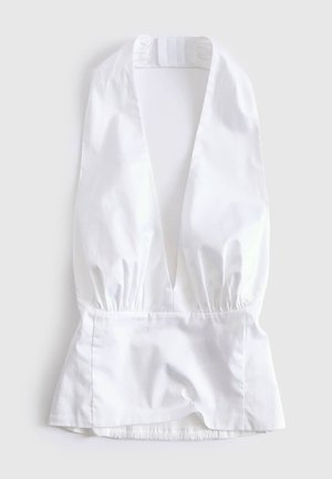 Witte mouwloze blouse met diepe V-hals, gerimpelde taille en peplumzoom, plat gelegd op een lichte achtergrond.