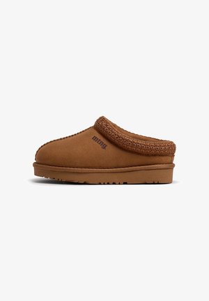Zapatilla marrón tipo slip-on con cuello de punto texturizado y logo "mmg." en el lateral, con suela de goma plana con patrón de dibujo.