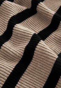 Beige- und schwarzgestreifter Stoff mit gerippter Textur, der abwechselnd breite und schmale Streifen aus einem weichen, gewebten Material zeigt.