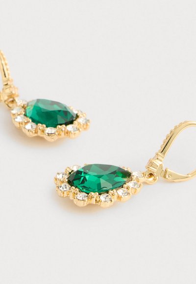 Gouden oorbellen met grote facetterende groene edelstenen omringd door kleine heldere kristallen, met haaksluitingen, op een witte achtergrond.