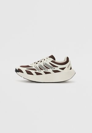 Hvid og brun atletiksneaker med tyk sål, mesh overdel og snørelukning, set fra ydersiden mod en ensfarvet baggrund.
