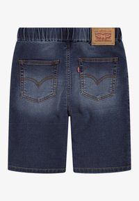 Pantalones cortos de mezclilla en azul oscuro con una cintura elástica. Presentan dos bolsillos traseros y un parche de cuero con la marca en la parte trasera de la cintura.