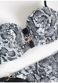 Czarny i biały komplet biustonosza i kostiumu kąpielowego z motywem węża, z formowanymi miseczkami, złotymi detalami oraz gładkimi czarnymi ramiączkami.