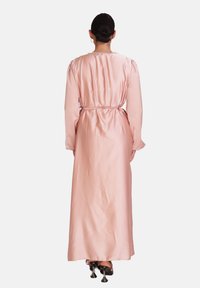 Lang pink satin kjole med lange ærmer, en snøret talje og glat tekstur. Har et hel længde design og subtile puff skuldre.