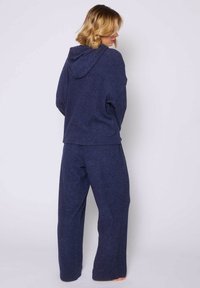 Marineblauw loungewear-set met een hoodie en wijdvallende broek. Zacht, textuurstof met een relaxte pasvorm zonder zichtbare hardware.