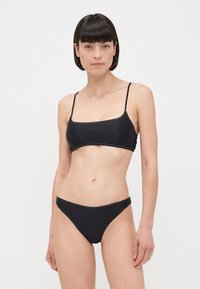 Zwart bikiniset met een kort topje in tankstijl met dunne bandjes en een bijpassende low-rise bikini onderkant, beide met contrasterende stiksels.