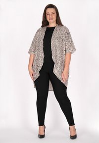 Könnyű, bézs színű kimono fekete leopárdmintával, rövid ujjakkal és nyitott elülső résszel, fekete leggings-el és magassarkúval párosítva.