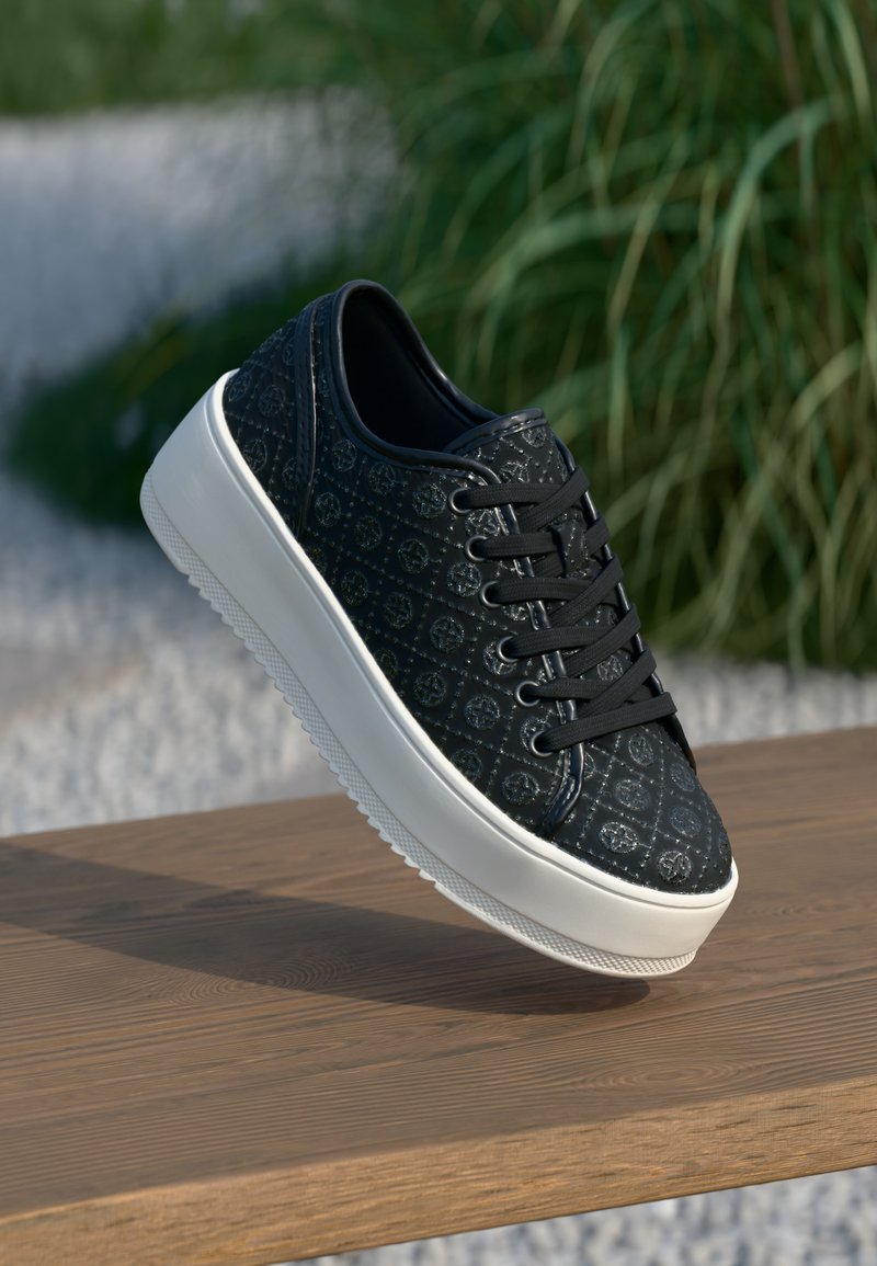 Svart sneakers med preget mønster og snørelukking. Hvit gummisåle med strukturert grep. Glatt lærtekstur og avrundet form.