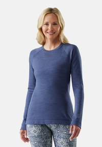 Long-sleeve blue athletic top with a round neckline, textured fabric, and raglan sleeves. Accented with a small logo near the wrist.