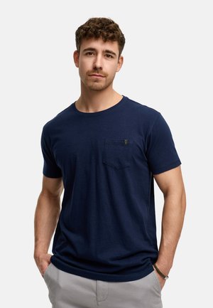 Camiseta de algodón azul marino con mangas cortas, cuello redondo y un detalle de bolsillo en el pecho. La tela es suave con una textura lisa.
