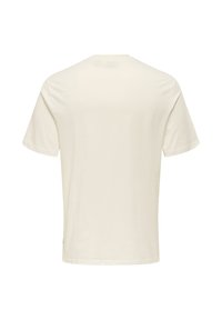 Camiseta de algodón crema de manga corta, cuello redondo y espalda lisa. Textura suave y ajuste regular, con detalles mínimos.