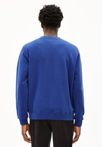 Blauer Sweatshirt mit langen Ärmeln, Rundhalsausschnitt und gerippten Bündchen. Weiche Textur und lockere Passform, mit einer Nahtverarbeitung am Saum.