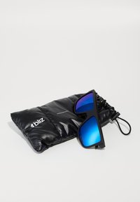 Mustat aurinkolasit sinisin peililinssin kanssa, lepäävät mustassa pehmustetussa kotelossa, jossa on logo "bliz" ja teksti "Performance Eyewear."