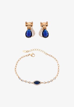Boucles d'oreilles en or rose en forme de renards avec des pierres bleues en forme de goutte et des accents de strass, assorties à un bracelet avec une pierre bleue.