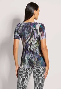 Kurze Ärmel Bluse im mehrfarbigen abstrakten Muster; aus glattem Stoff und mit figurbetonter Silhouette. Tragen Sie dazu gemusterte schwarz-weiße Hosen.