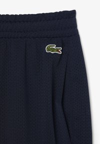 Pantalones cortos deportivos en color navy, fabricados en una malla transpirable, con cinturilla elástica y un pequeño logo bordado de cocodrilo en el lado.