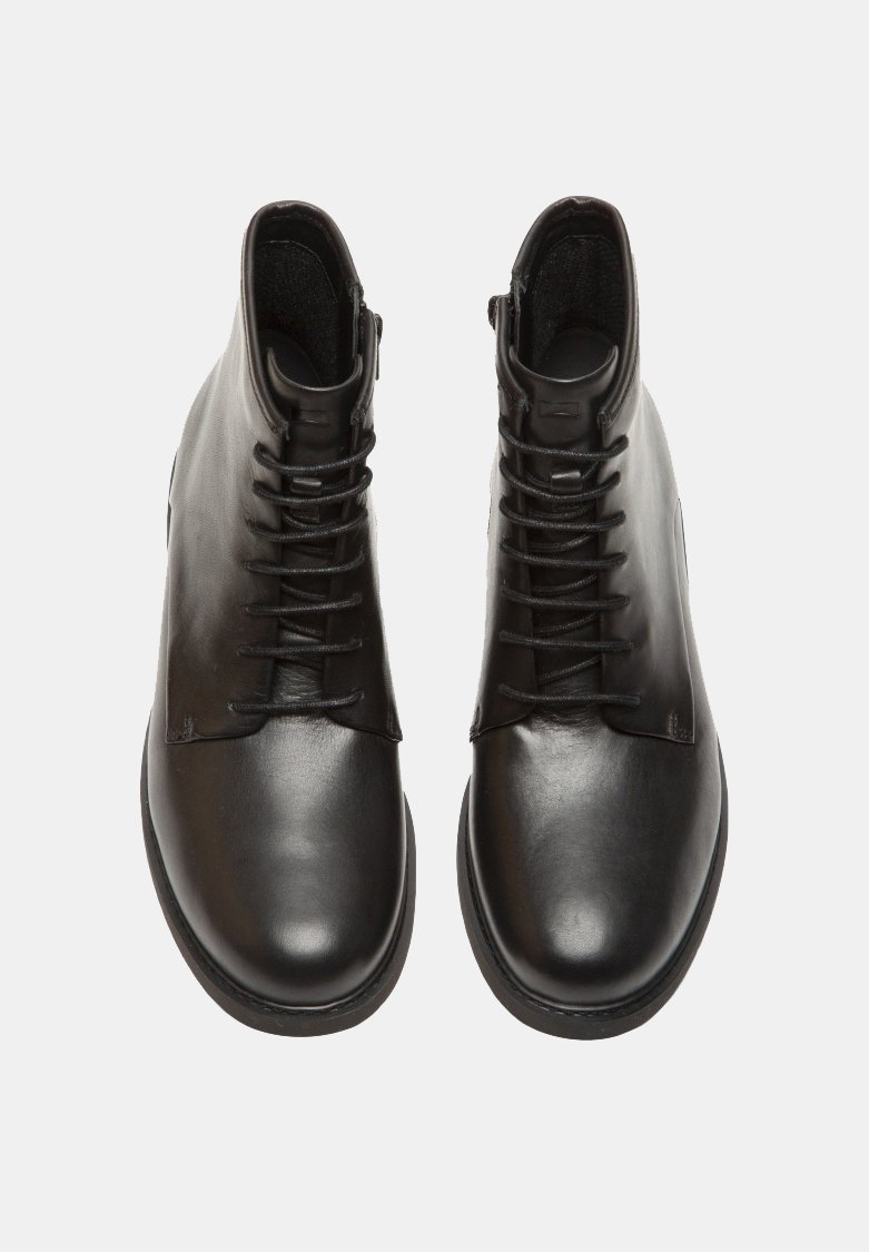 Botas de tobillo de cuero negro con una superficie lisa, punta redonda y un cierre de cordones en la parte delantera, con un tacón ligeramente elevado.