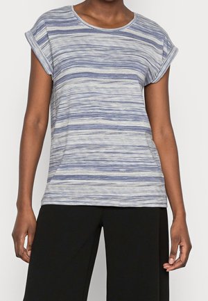 Femme portant un haut à manches courtes rayé horizontal bleu et blanc, associé à un pantalon noir à jambes larges, sur un fond uni.