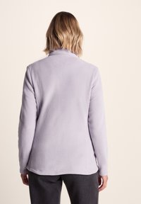 Light purple fleece jacket with a high collar and long sleeves. Soft texture with a straight cut and no visible closures or embellishments.