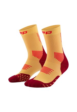 Yellow and red sports socks with textured patterns, ribbed cuffs, and reinforced toe and heel areas. High-performance design for athletic use.