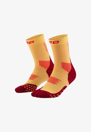 Gelbe und rote Sportsocken mit strukturierten Mustern, gerippten Bündchen und verstärkten Zehen- und Fersenbereichen. Hochleistungsdesign für den sportlichen Einsatz.