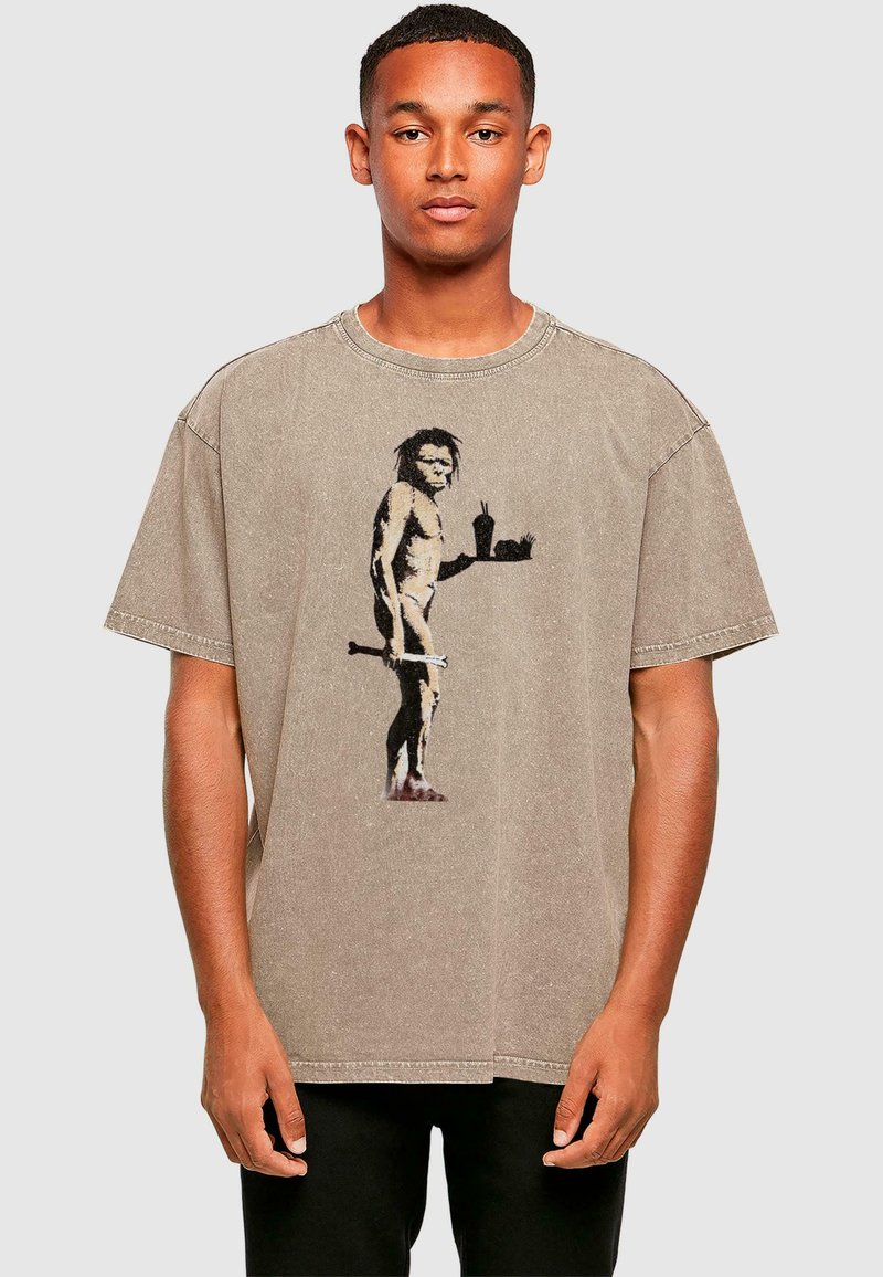 Taubfarbendes, übergroßes Baumwoll-T-Shirt mit einem Motiv eines Höhlenmenschen, der ein Getränk hält. Kurze Ärmel, runder Halsausschnitt und ausgewaschene Textur.