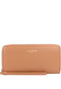 Tan leather wallet with a smooth texture, rectangular shape, gold "Lancaster Paris" logo, and a zipper closure. Includes wrist strap.