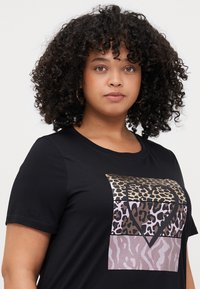 Schwarzes Kurzarm-T-Shirt mit einem Herzdesign, das auf der Vorderseite mit Leoparden- und Tiermustern in goldenen, braunen und rosa Farbtönen verziert ist.
