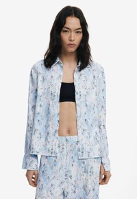 Light blue floral-patterned shirt made of soft fabric, featuring a button-down front and long sleeves with a relaxed fit.
