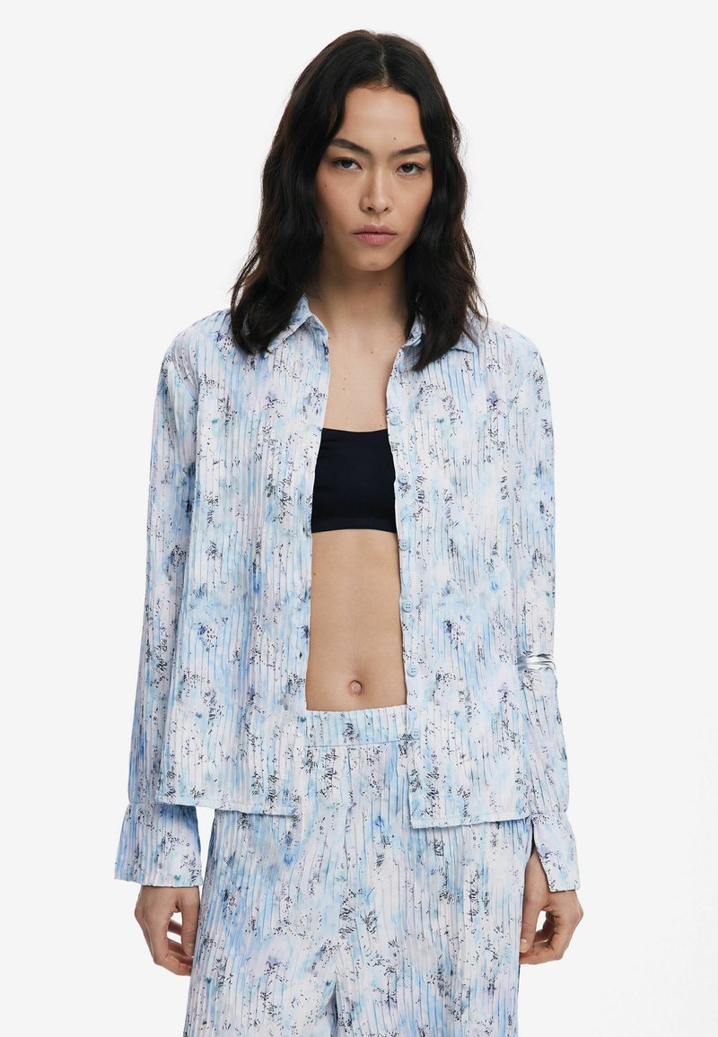 Light blue floral-patterned shirt made of soft fabric, featuring a button-down front and long sleeves with a relaxed fit.