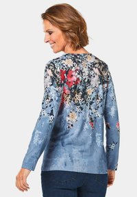 Langärmlige Blumenbluse in Blau mit mehrfarbigem Blumenmuster. Verfügt über einen runden Halsauschnitt, ein weiches Material und eine lässige Passform.