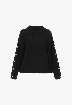 Fekete, vastag kötésű pulóver magas nyakkal és aranygombokkal, amelyek hosszában futnak mindkét oversize ujjon.