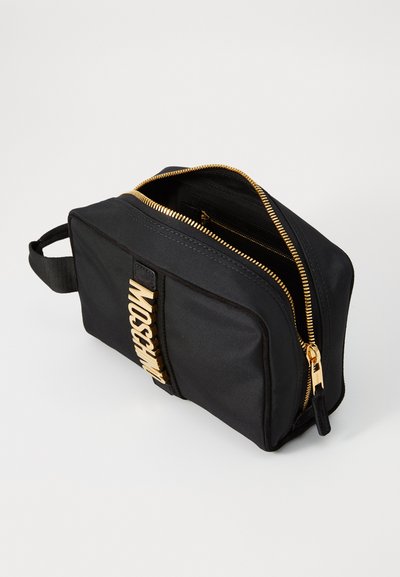 Geantă cosmetică din nailon negru cu un fermoar auriu, având un logo auriu proeminent "MOSCHINO" pe lateral și o mânere robust pentru portabilitate.