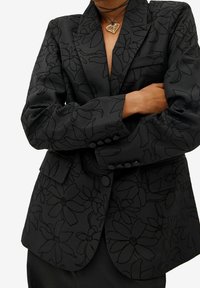 Schwarzer Blazer mit einem tonal floralen Muster, strukturierter Silhouette, Reverskragen und geknöpften Manschetten. Weicher, texturierter Stoff mit detaillierter Nahtverarbeitung.