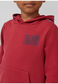 Rode sweatshirt van katoen, met een voorzak en een grafische print met de tekst "BIG SHOW UNDERDOME" in het blauw. Zacht materiaal, casual ontwerp.