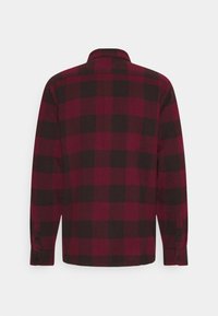 Chemise en flanelle à manches longues avec poignets boutonnés, motif à carreaux rouge et noir, vue de dos.