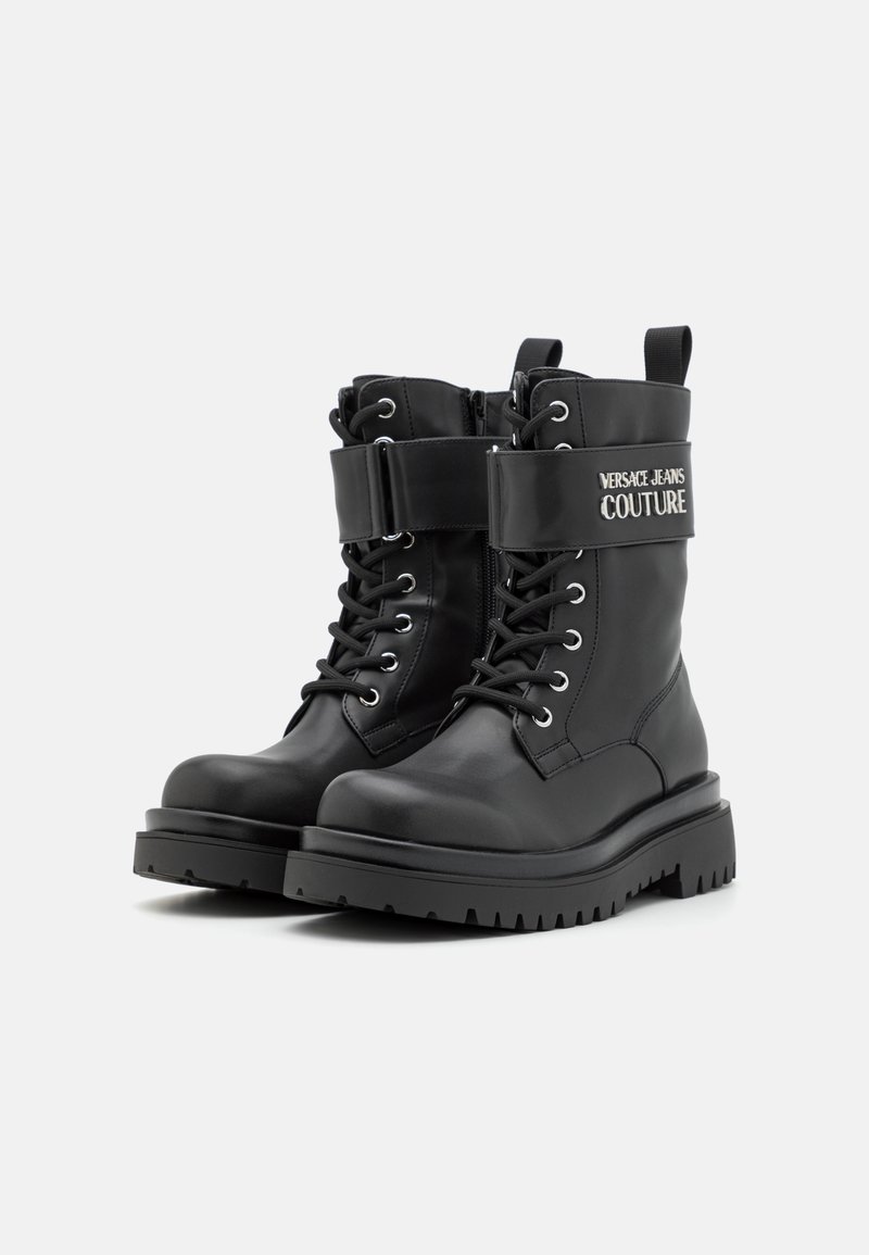 Schwarze Leder-Kampfstiefel mit einer Schnürung an der Vorderseite, gepolstertem Knöchel, breitem schwarzen Riemen mit Logo und Gummisohle für bessere Bodenhaftung.