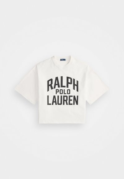 Izgriezta balta kokvilnas T-krekla ar izteiksmīgu melnu tekstu "RALPH" virs "POLO LAUREN". Īsas piedurknes, apaļa izgriezuma kakla daļa, vienkārša dizaina.