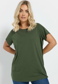 Oliven grøn kortærmet t-shirt lavet af blødt stof, med en afslappet pasform og en rund halsudskæring, parret med blå jeans.