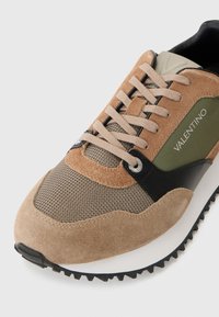 Brown and black athletic sneaker featuring suede, mesh, and leather materials, with an olive green accent and textured rubber sole.