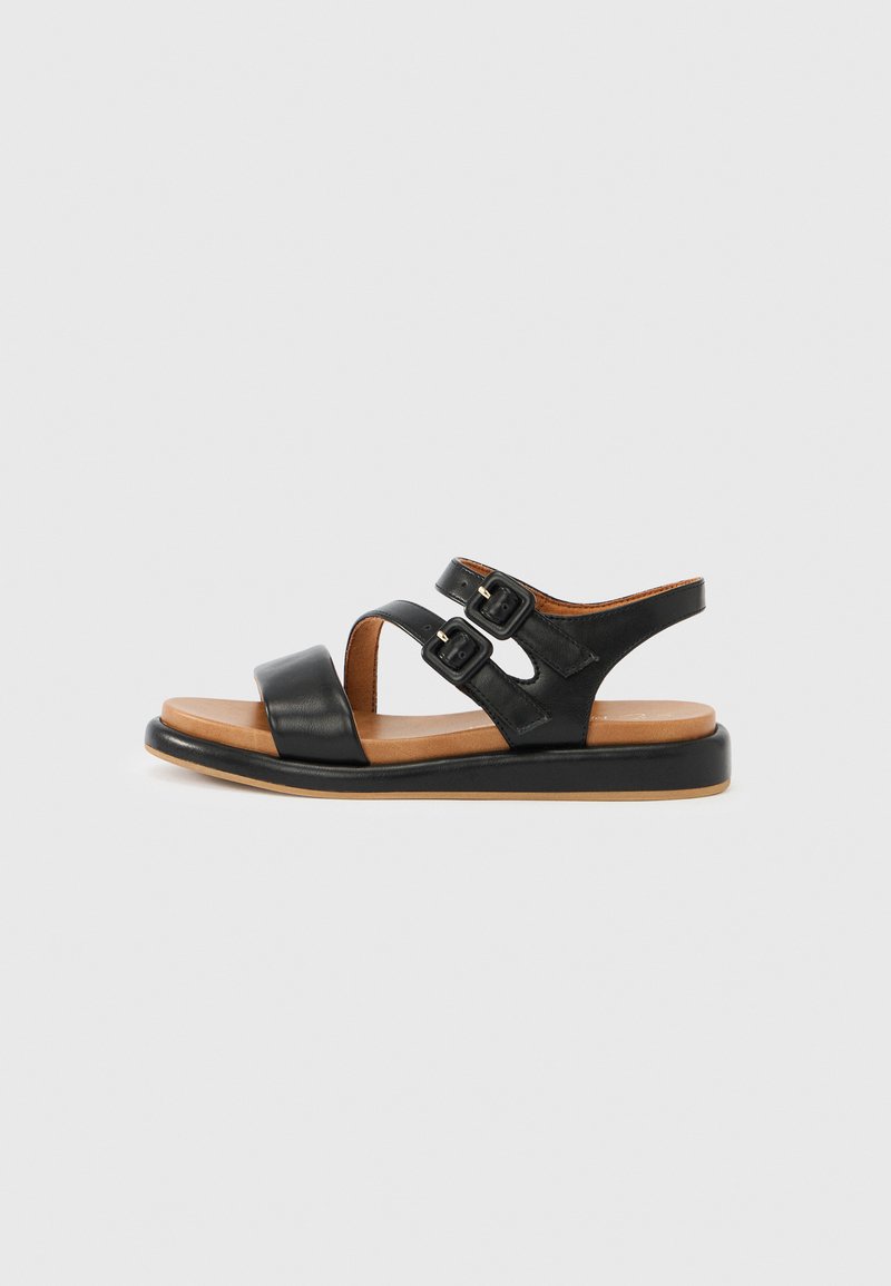 Μαύρο δερμάτινο σανδάλι με δύο ρυθμιζόμενους ιμάντες με αγκράφες, επίπεδη καφέ σόλα, ανοιχτή σχεδίαση δαχτύλων και λεία υφή. Κατάλληλο για καθημερινή χρήση.