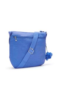 Borsa a tracolla blu con tracolla regolabile, tasca a zip frontale e un morbido portachiavi a pompon attaccato di lato.