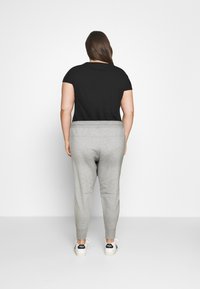 Top preto de mangas curtas combinado com calças de jogging cinzas. As calças apresentam um corte ajustado e uma cintura elástica. Ténis brancos completam o visual.