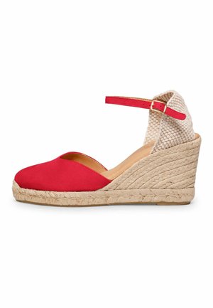 Sandalia cuña cerrada de color rojo con tacón tejido beige, correa en el tobillo y hebilla, sobre fondo blanco.