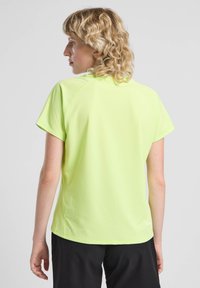 Maglietta sportiva a maniche corte, verde lime, realizzata in materiale leggero, con collo a giro e cuciture piatte, e orlo leggermente curvato.