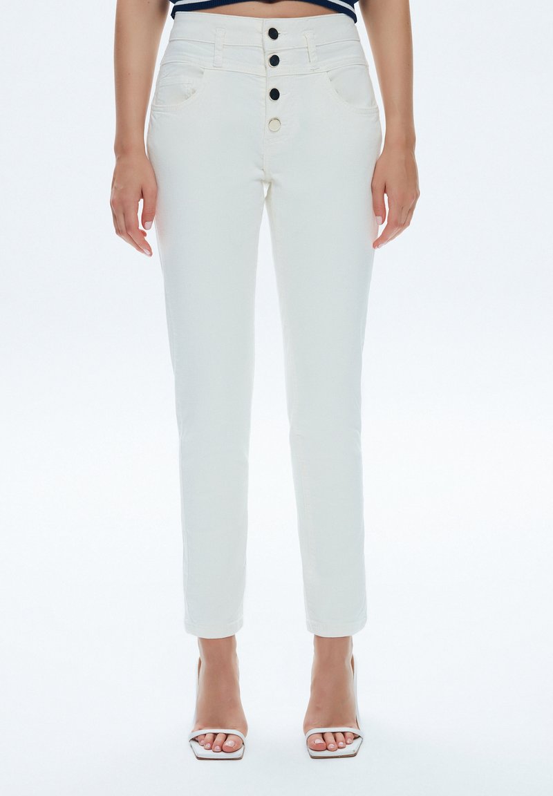 Pantalones de mezclilla blanca con un diseño ajustado, que presentan una cintura alta, tres botones negros y bolsillos frontales. Textura suave y piernas ajustadas.