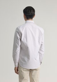 Camisa de manga larga a rayas en colores pastel claros, con cuello abotonado, puños reforzados y un diseño ajustado, hecha de tela de algodón.