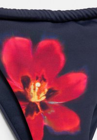 Donker marineblauwe stof met een grote, levendige rode bloemenprint met gele en zwarte details in het midden.