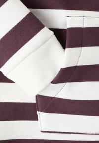 Látka s pruhy v barvě vínové a bílé, s žebrovaným bílým límcem a manžetami. Hladká textura, přesné švy na límci a čisté zakončení.