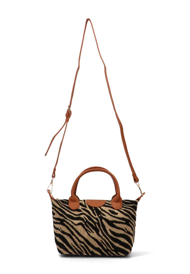 Bolso de tela con estampado de cebra, con asas de cuero marrón y correa ajustable. Presenta una forma estructurada y una textura suave.